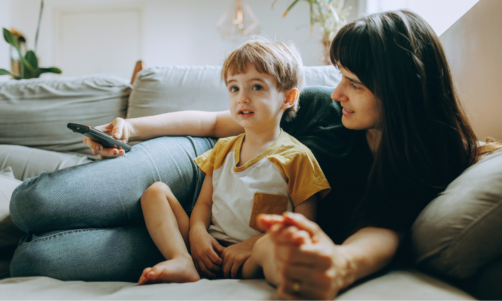Criança assistindo desenho com responsável ao lado